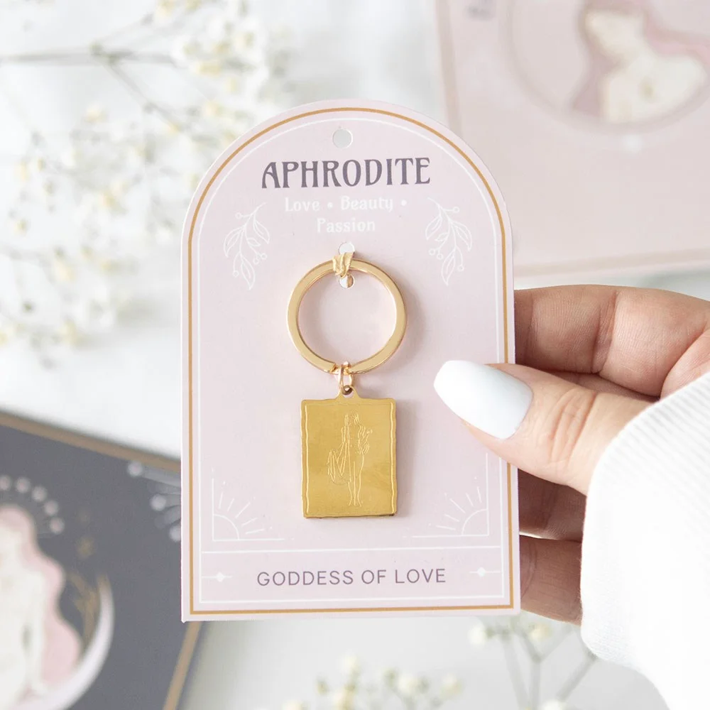 Gold-toned Aphrodite goddess keyring with detailed pendant on a matching backing card for gifting or personal use