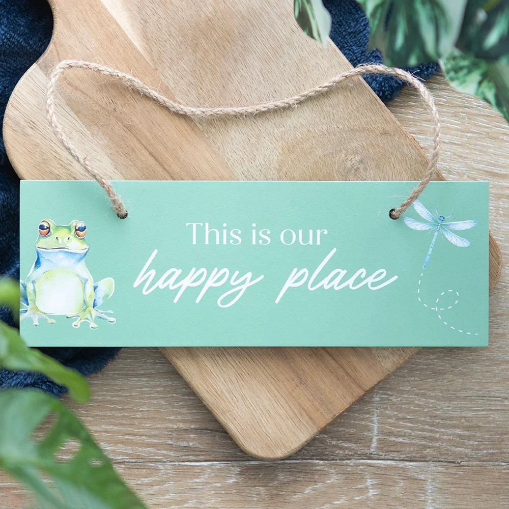 Light green happy place hanging sign with sitting frog, dragonfly, and rustic rope hanger on MDF background