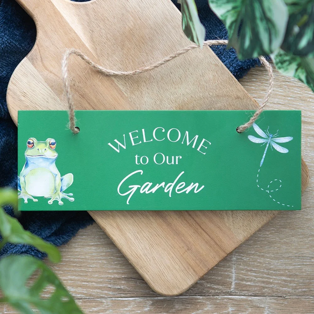Green garden welcome sign with sitting frog, dragonfly, and rustic rope hanger for patio or entryway decor