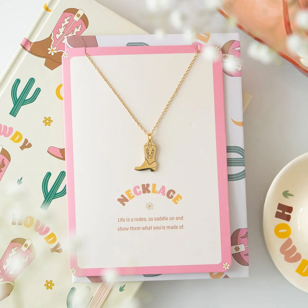 Cowboy boot necklace with dainty pendant displayed on greeting card reading "Life is a rodeo" with included envelope
