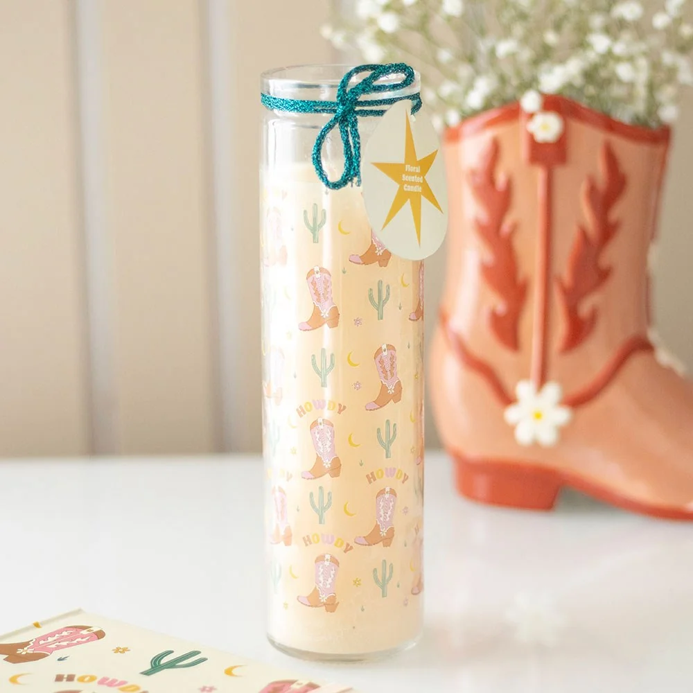Floral scented candle in a white tube with cowboy boot print and Howdy greeting, 50-hour burn time