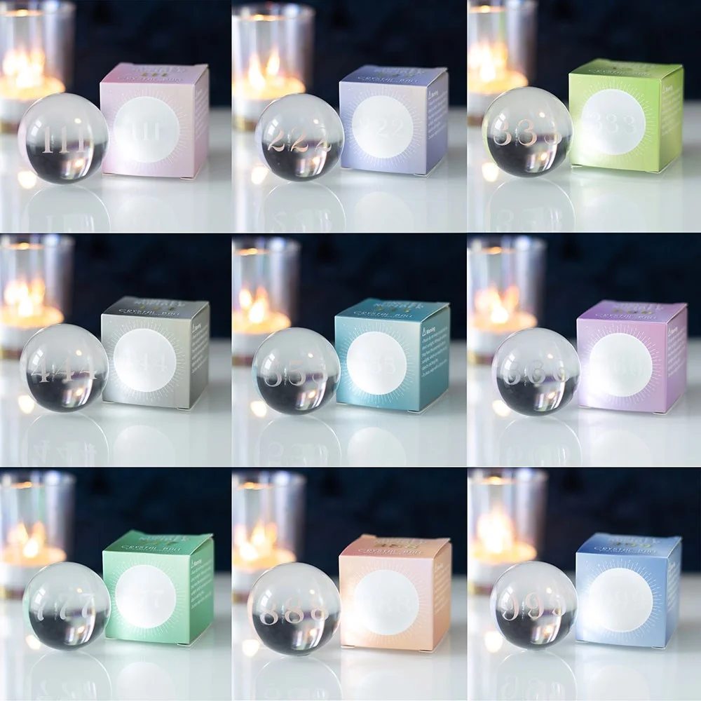 Set of 9 angel number crystal balls with laser-engraved numbers 111 to 999 arranged on a white background