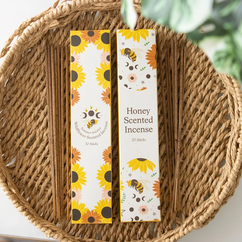 Set of 2 packs of honey and wildflower incense sticks with floral and honeycomb designs on packaging