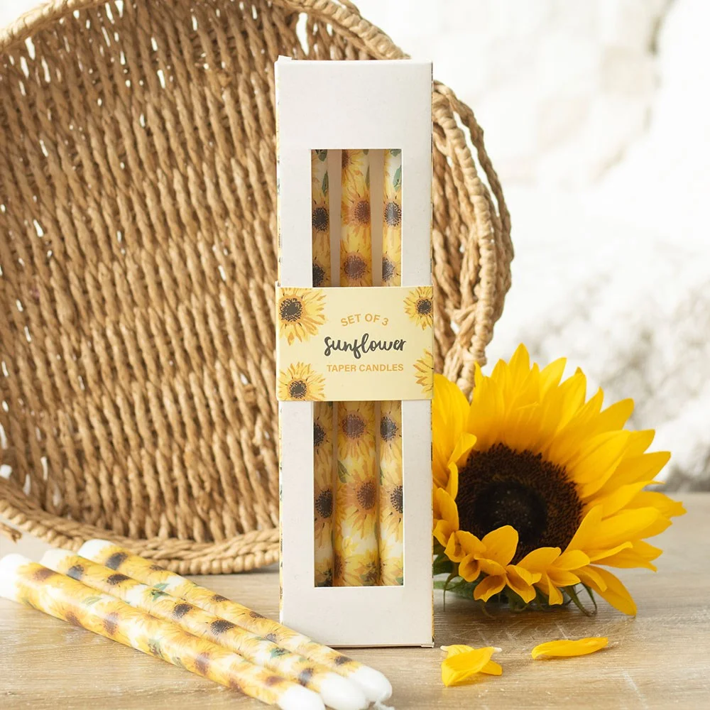 Set of 3 unscented sunflower taper candles with bright yellow floral design on slender wax sticks