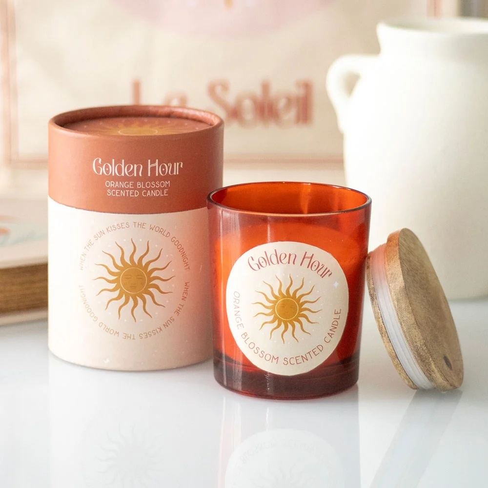 Golden Hour orange blossom candle in 12.5cm glass jar with cork lid, next to matching cardboard gift tube on white background