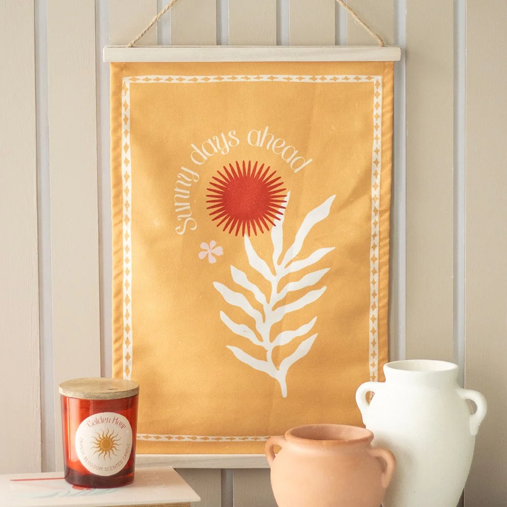 Sunny days wall hanging with vibrant orange sun and leaf flower design and uplifting text on white background