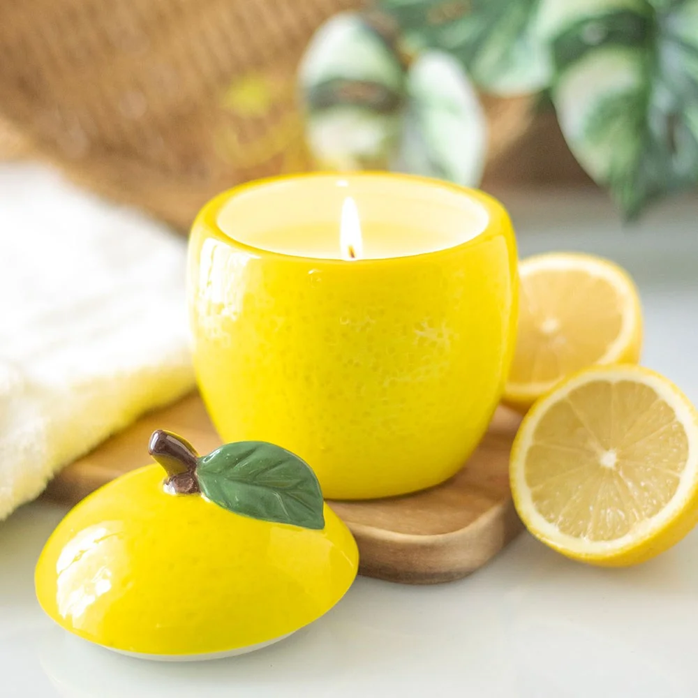 Lemon shaped candle jar with yellow textured surface and green leaf detail on top, designed to look like a fresh lemon