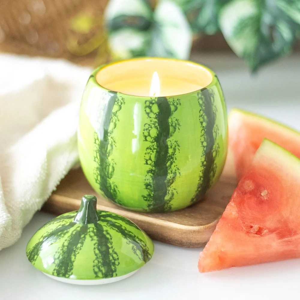 Watermelon candle jar shaped like a sliced watermelon with green rind and red interior, decorative scented candle in kitchen setting