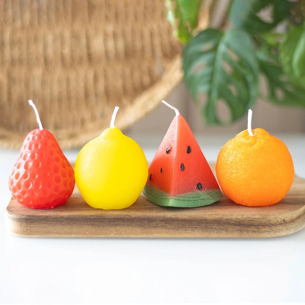 Set of 4 unscented fruit shaped candles in strawberry, orange, lemon, and watermelon designs on white background