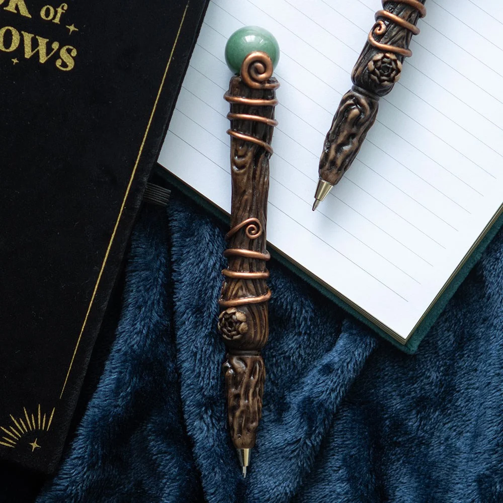 Green aventurine wand pen with crystal tip, magic wand design, resting on a moon and star patterned gift box