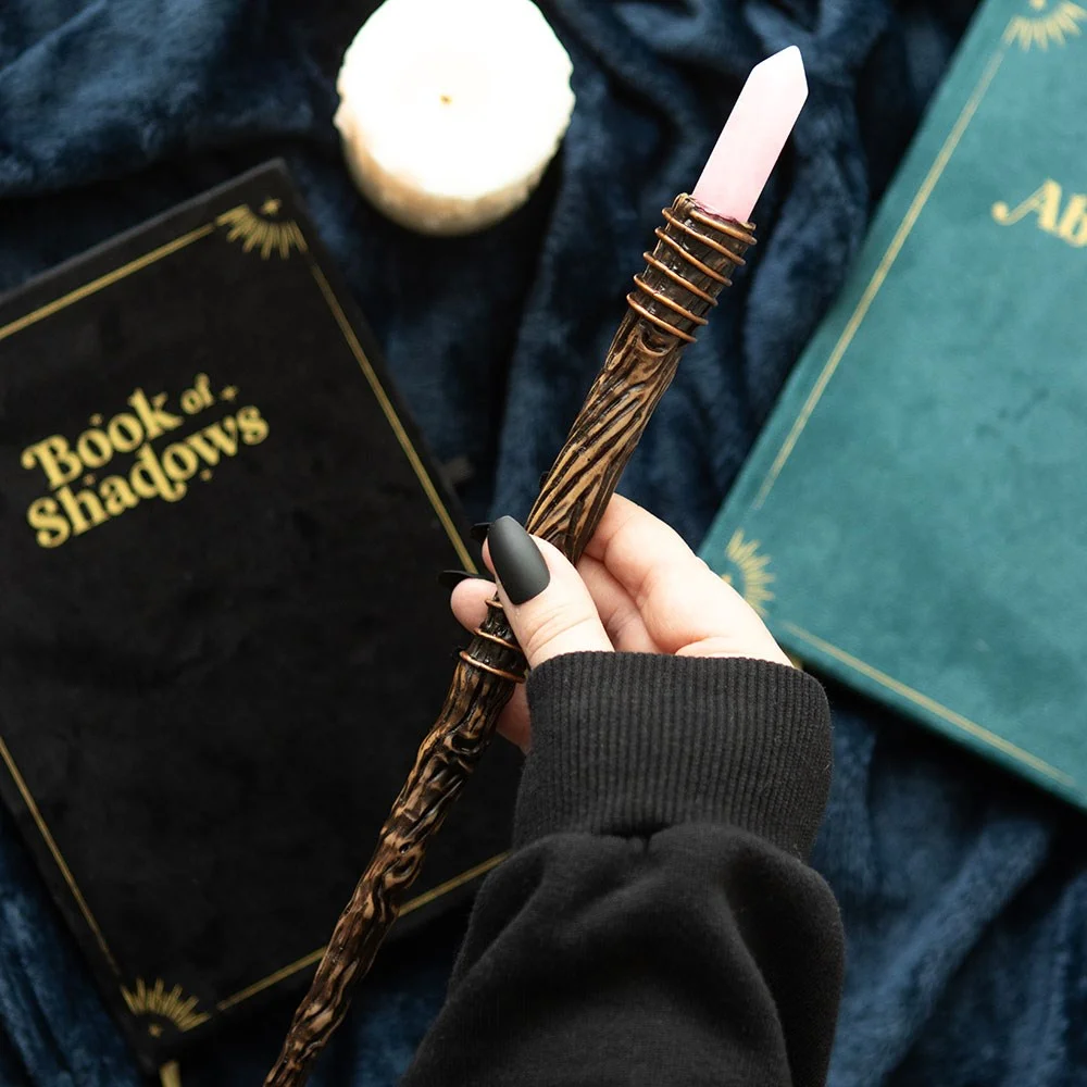 Slender rose quartz wand with a pointed crystal tip on a white background for romance and self-love energy work