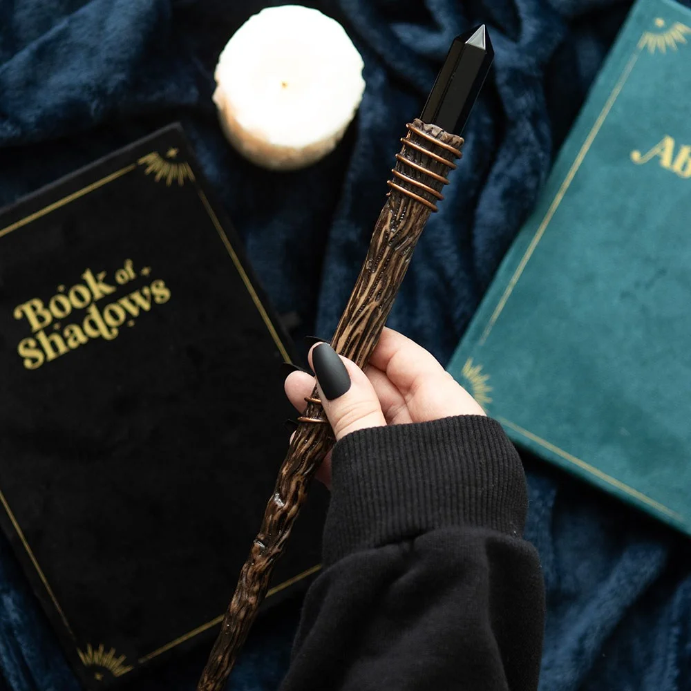 Thin black obsidian wand with slender crystal point on white background, designed for energy protection and clarity