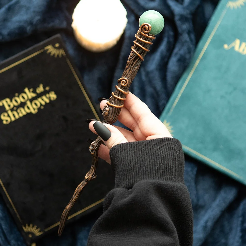 Green aventurine wand with smooth crystal and wooden handle, displayed with a black storage pouch on white background