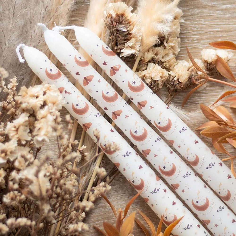 Set of 3 elegant harvest moon taper candles in warm autumnal colors, standing upright on a white background