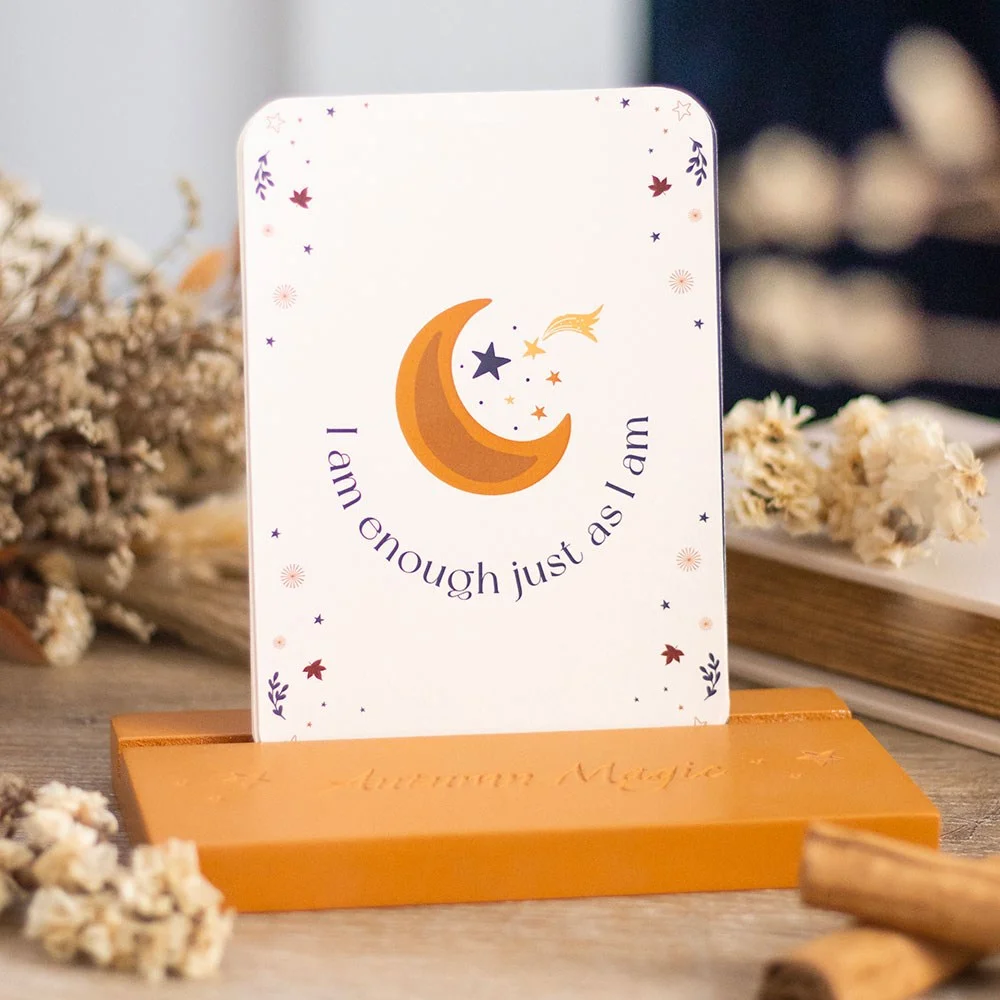 Autumn-themed affirmation cards set displayed on a wooden stand with warm, inspiring designs and text