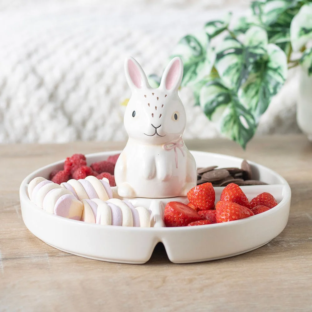 White ceramic bunny chip and dip dish with bunny-shaped dip cover and surrounding sections for snacks on a table