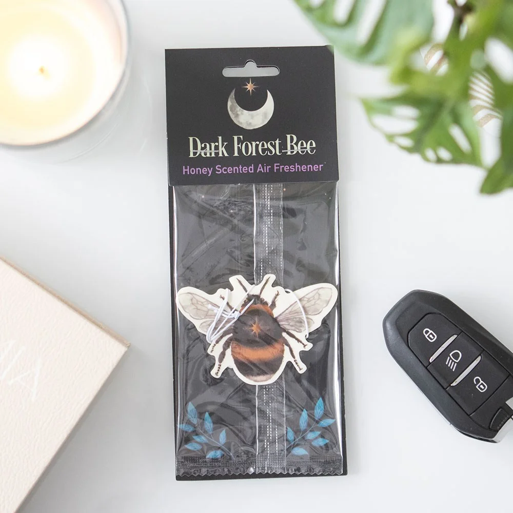 Honey scented air freshener shaped like a bee with forest and honeycomb design on a white background