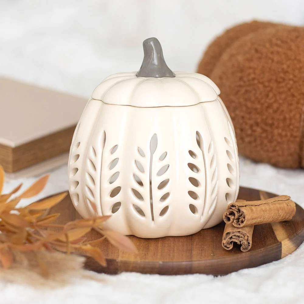 Ceramic pumpkin oil burner in cream finish with cut‑out design, holding a scented wax melt.