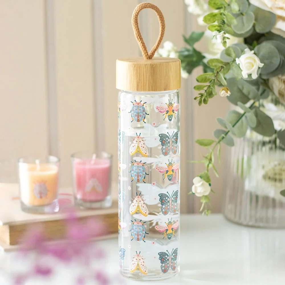 Glass water bottle with floral bug print, bamboo lid, and carrying loop, 650ml capacity on white background
