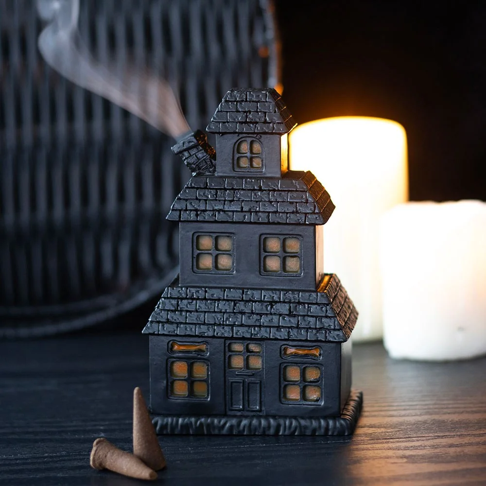 Black resin haunted house incense holder with smoke curling through chimney, designed for standard incense cones