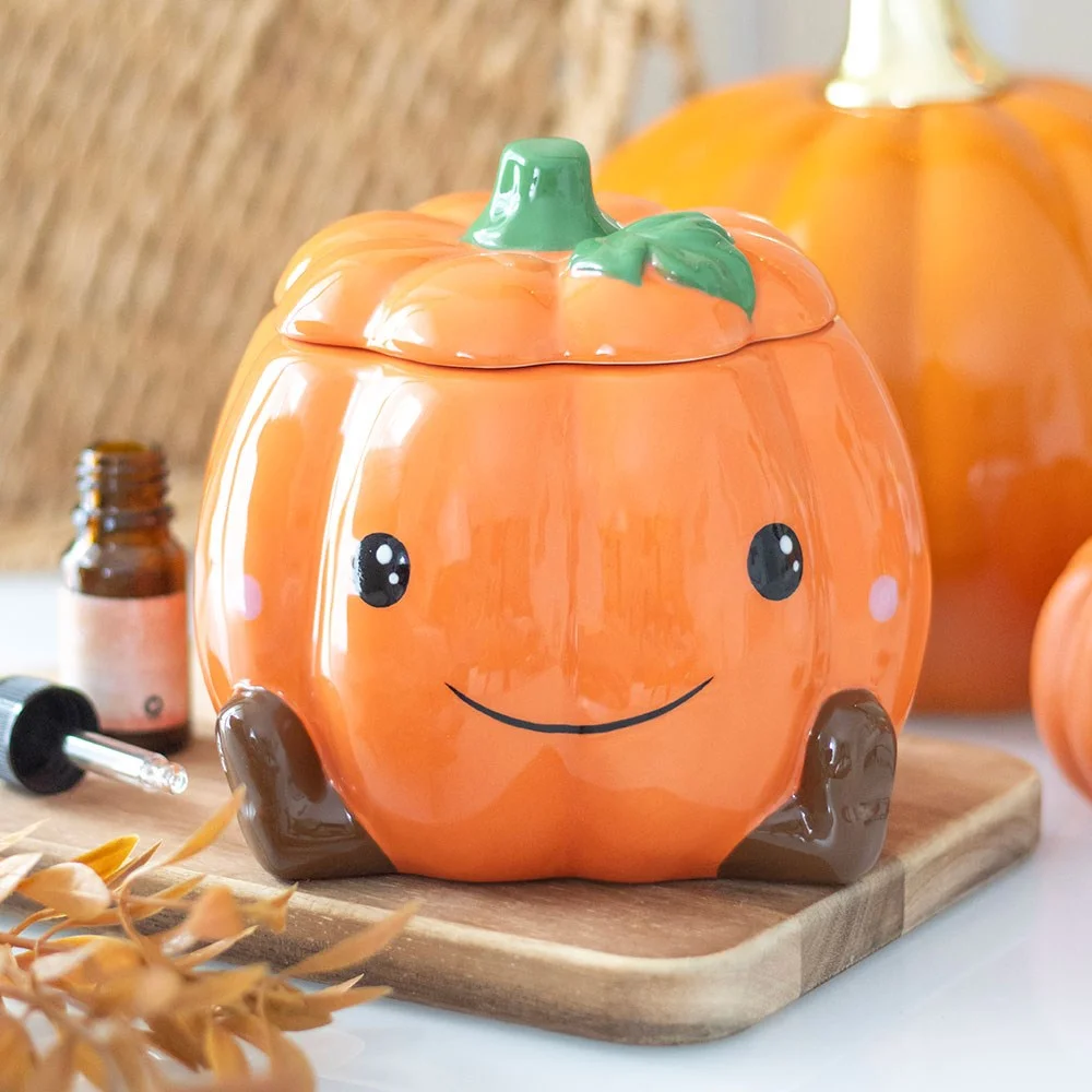 Cute ceramic pumpkin oil burner with smiling face and star cut-outs, designed for wax melts and fragrance oils