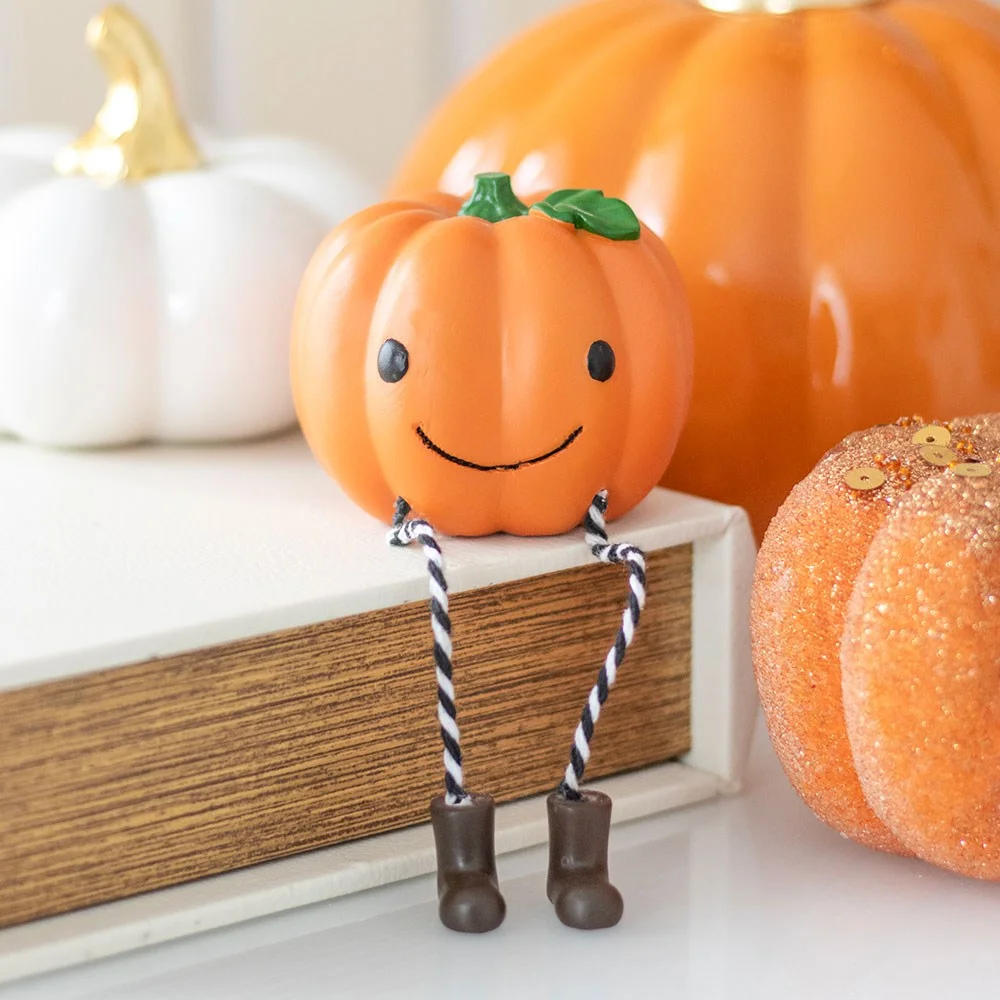 Smiling pumpkin shelf sitter ornament with striped legs and boots, perfect for Halloween decor on shelves or mantelpieces