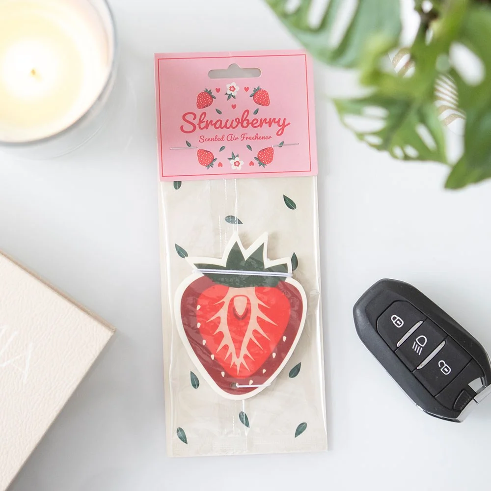 Red strawberry-shaped air freshener with green leaves, designed to freshen car interiors with a fruity scent