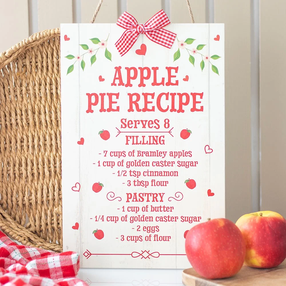 Farmhouse kitchen sign with apple pie recipe text and autumn-themed design hanging on a wall