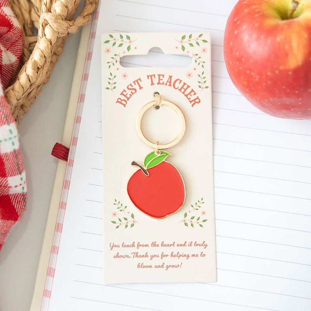 Red enamel teacher apple keyring with gold trim and keyring loop on white background