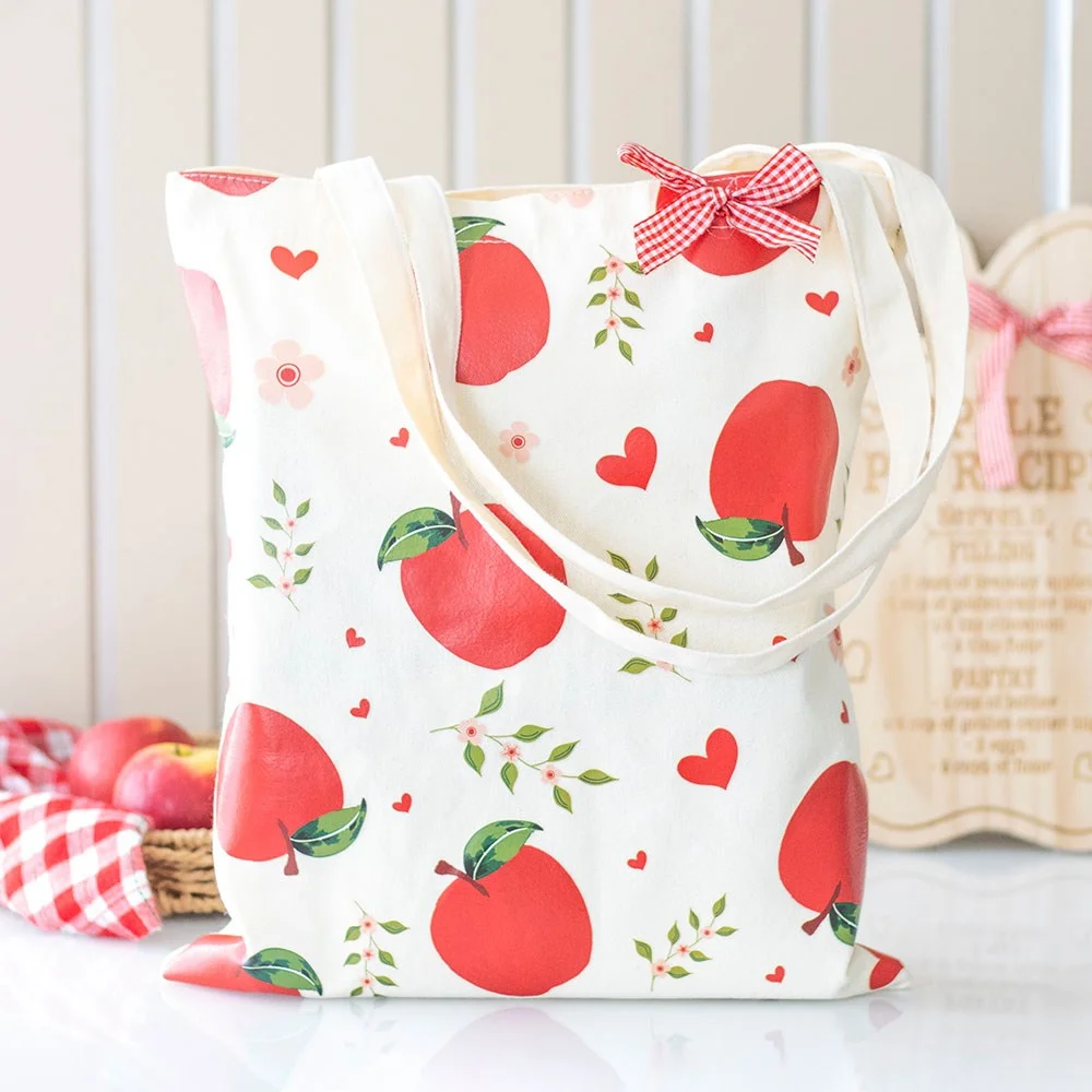 Red apple print tote bag with gingham bow on white polycotton fabric, eco-friendly and stylish accessory
