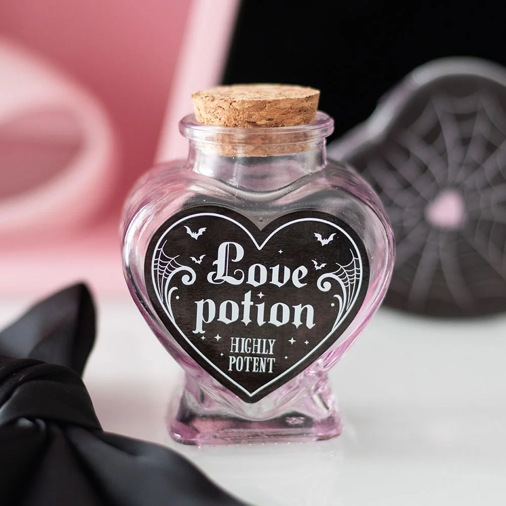 Decorative glass love potion bottle shaped like a heart with pink and black mystical design and intricate details