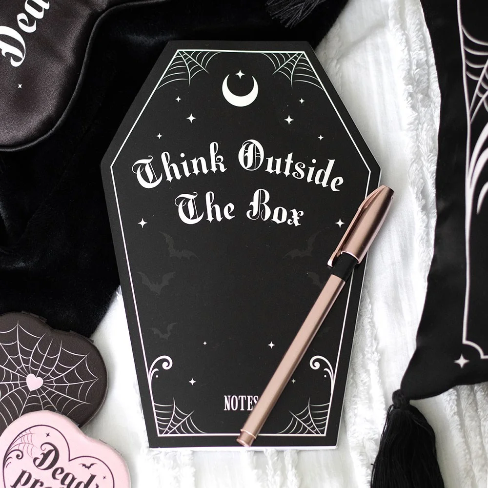 Black coffin shaped notebook with pink accents and soft cover, ideal for journaling or doodling