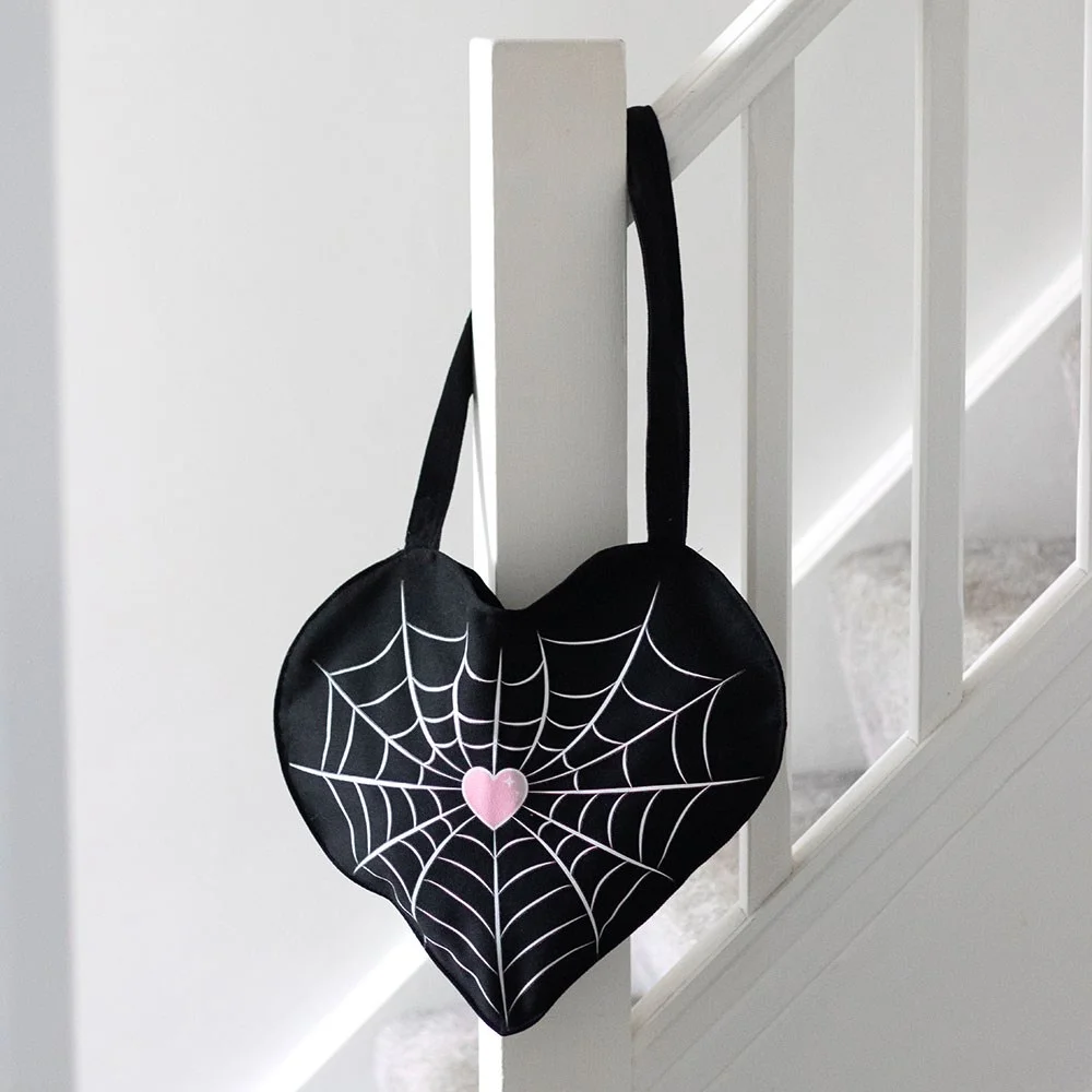 Black satin tote bag with white spiderweb heart design, lightweight fabric, two handles for carrying essentials