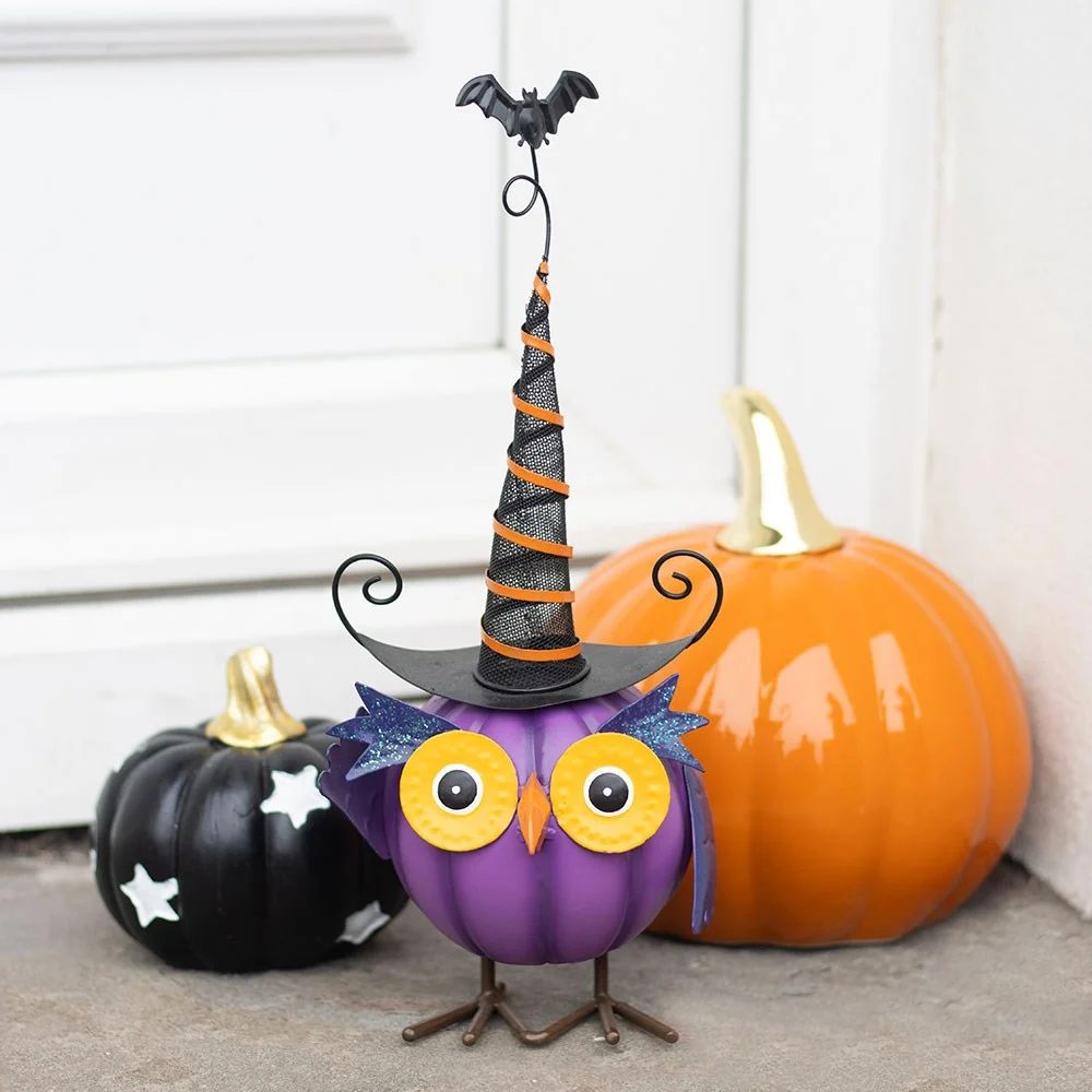 Purple owl ornament with yellow eyes wearing a curly witch hat, sitting on a white surface against a plain background