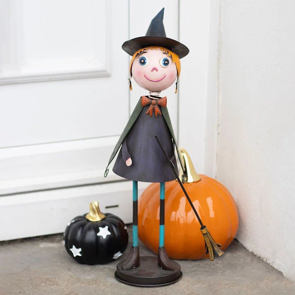 Metal witch ornament with pointy hat, flowing cape, and broomstick, designed for Halloween décor on a white background
