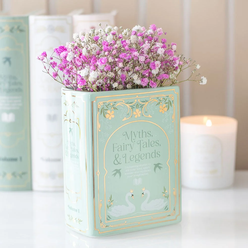 Green book shaped vase – green ceramic vase in book shape, holding fresh blooms, displayed on a bookshelf.