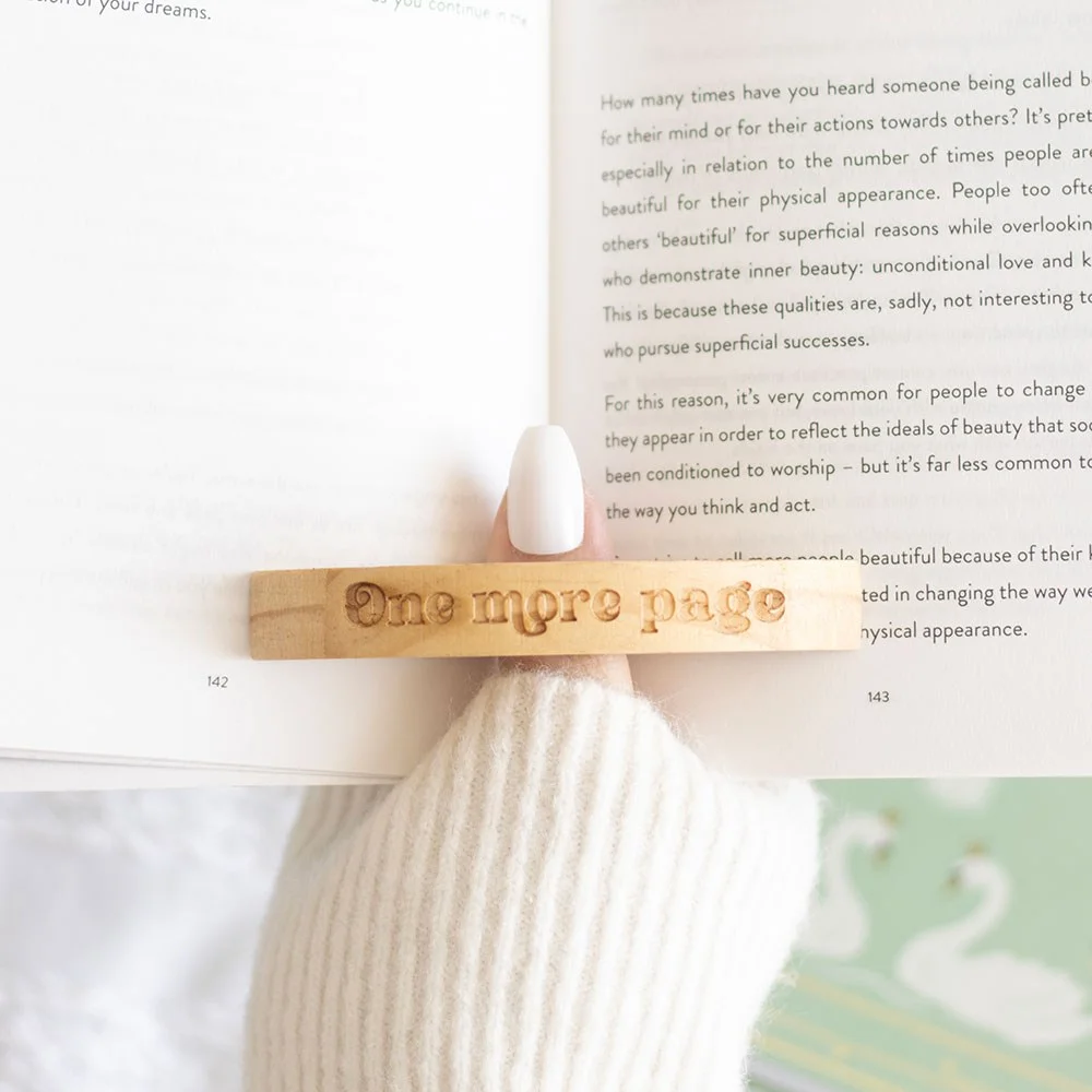 Wooden thumb page holder engraved with 'Book Worm', used to keep pages spread for one‑handed reading.