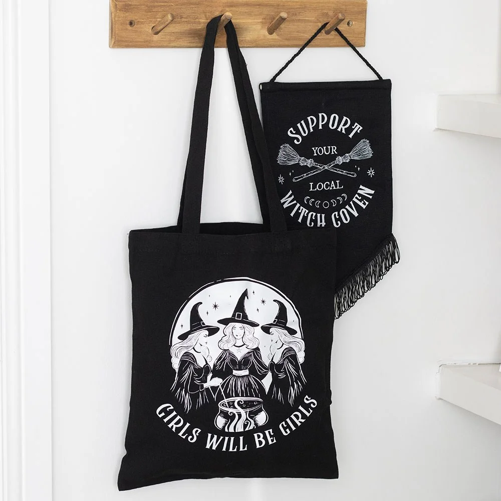 Bold black witchy tote bag featuring three spell‑casting witches and the phrase 'Girls Will Be Girls'.