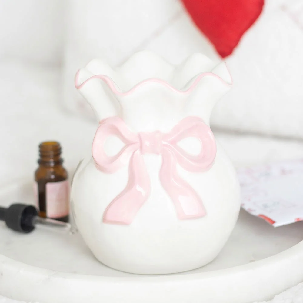 White ceramic oil burner decorated with a soft pink bow, perfect for everyday fragrance and Valentine’s Day.