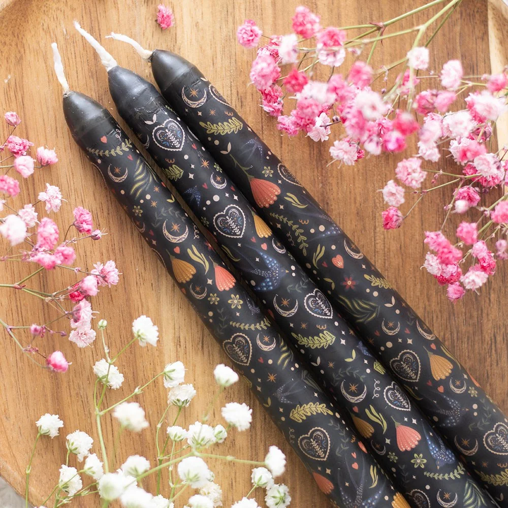 Set of 3 black taper candles with midnight folk-inspired print, unscented, shown upright on white background