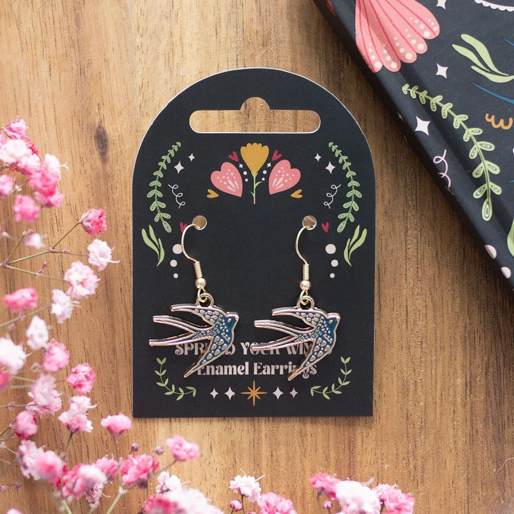 Pair of blue swallow earrings shaped like birds with spread wings on a white background
