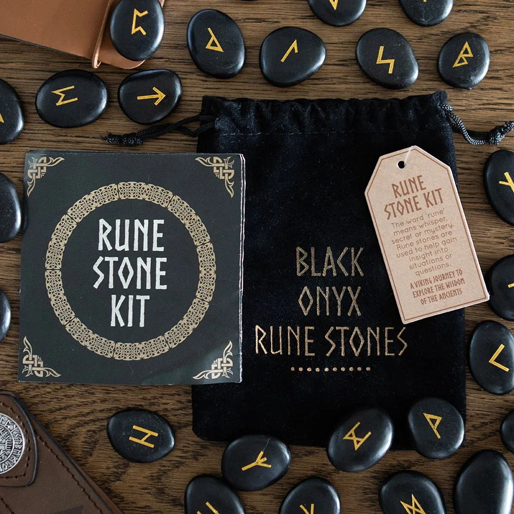 Set of 25 polished black onyx rune stones with Norse symbols displayed next to a black drawstring pouch