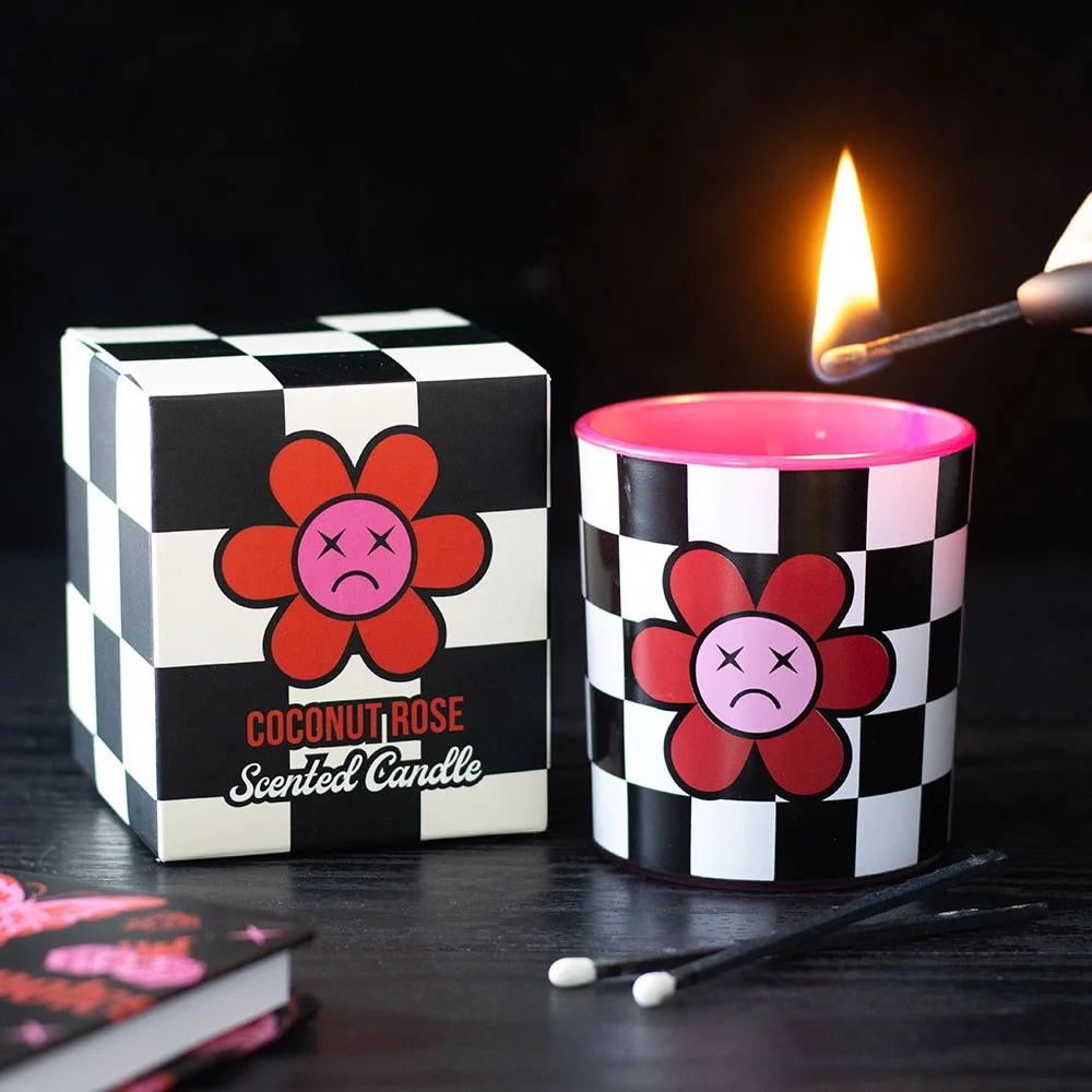 Checkerboard sad flower design on coconut rose candle in glass jar with wooden lid on white background
