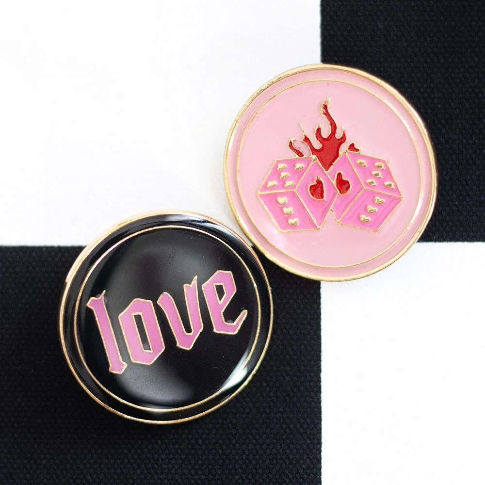 Pink flaming dice and black 'love' text pin badge set on white background for jackets or bags accessory