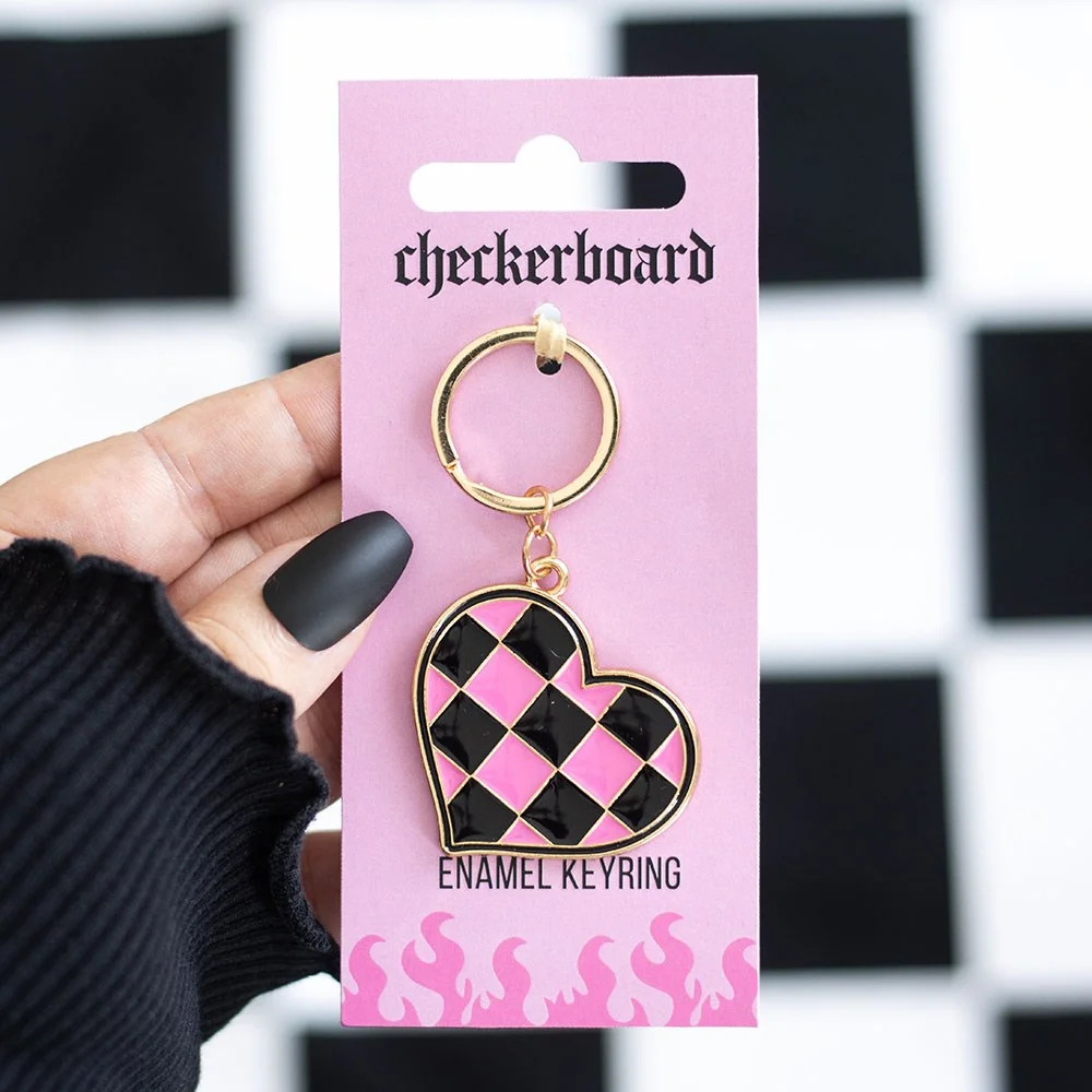 Checkerboard heart keyring in black and pink with a metal clip attached, styled with Y2K pop-punk vibes