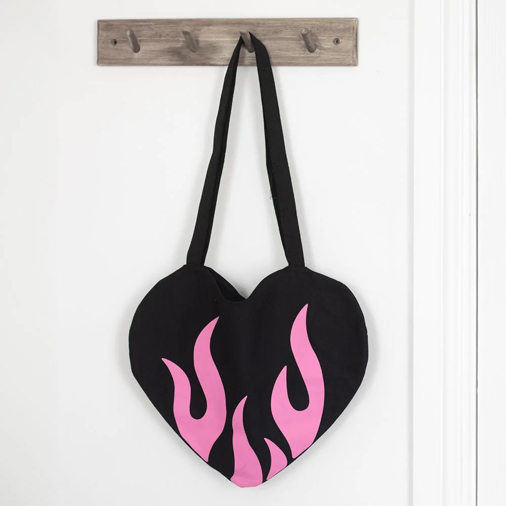 Black satin burning heart tote bag with bold red and orange flame design, lightweight with pop-punk style