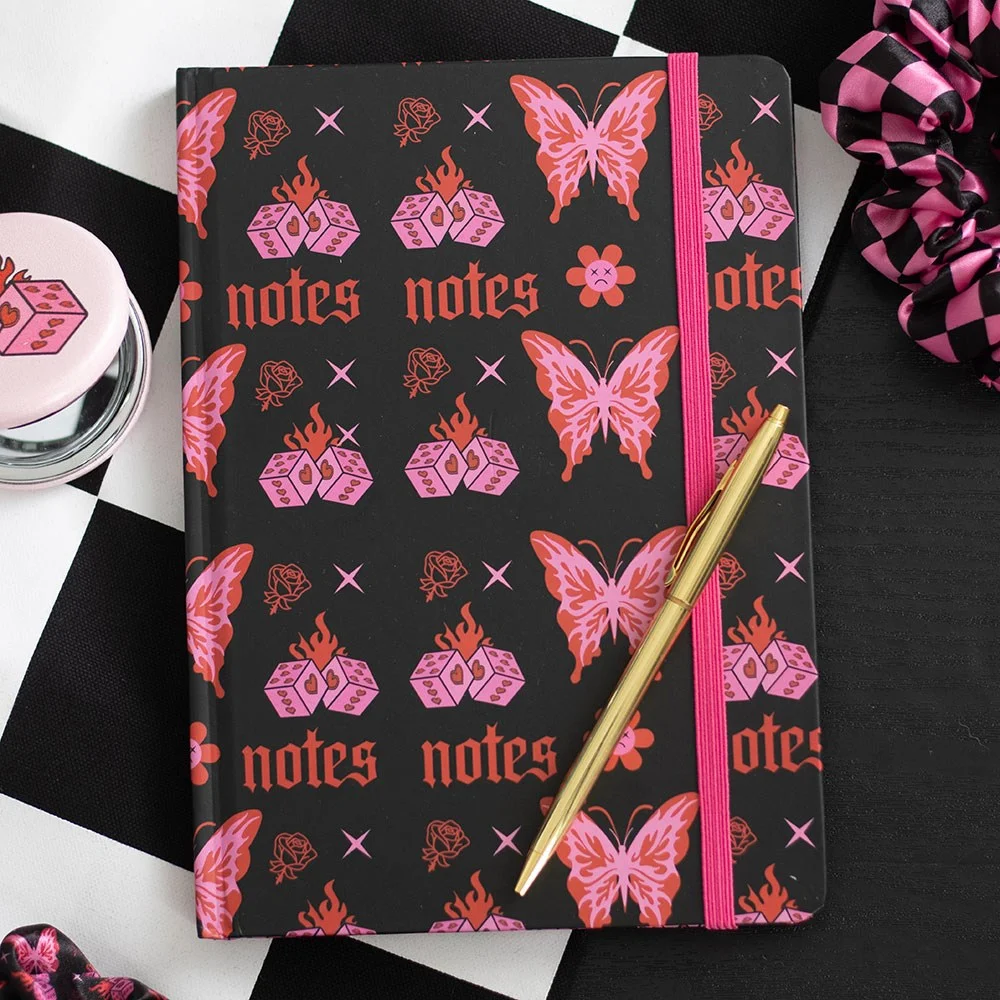 A5 notebook with hot pink and red Y2K butterfly, dice, and alt-style icon pattern on the cover