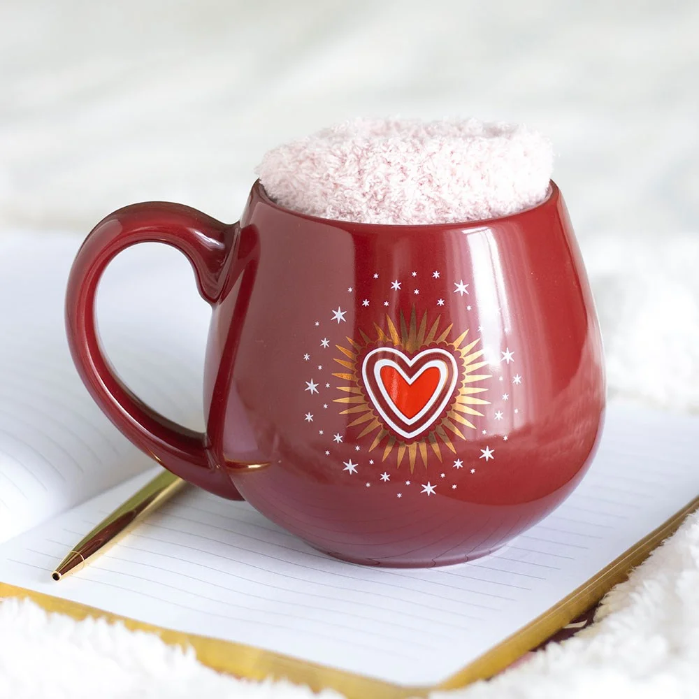 Pink socks next to a white mug with a red sacred heart design heart mug and socks set for Valentine’s Day