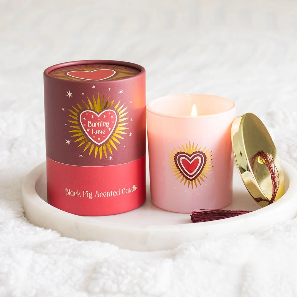 Burning Love black fig scented candle in blush pink glass jar with gold lid and tassel, sacred heart design on front