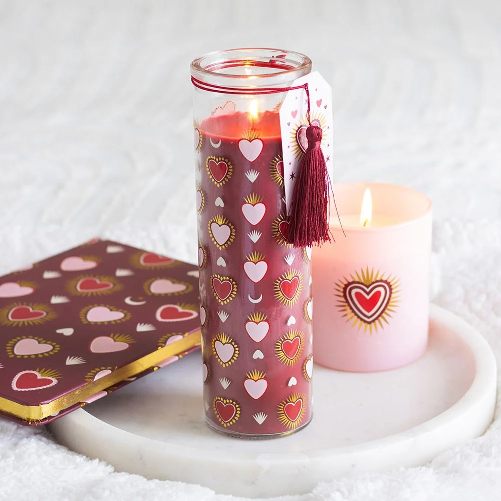 Tall glass tube black fig candle with sacred heart design and metallic accents on a white background